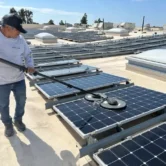 Professional technician cleaning PV panels with specialized solar panel cleaning equipment.