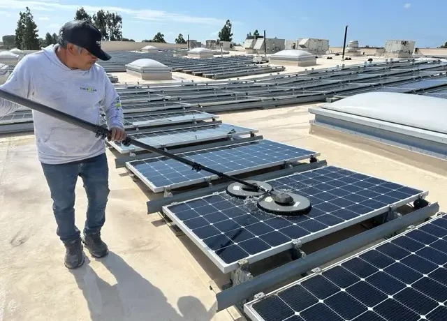Professional technician cleaning PV panels with specialized solar panel cleaning equipment.