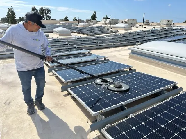 Professional technician cleaning PV panels with specialized solar panel cleaning equipment.